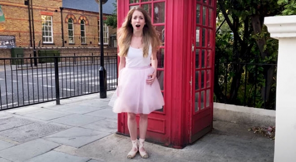 한 발레리나가 전통적인 영국의 붉은 공중전화 부스 앞에서 노래하고 있다.